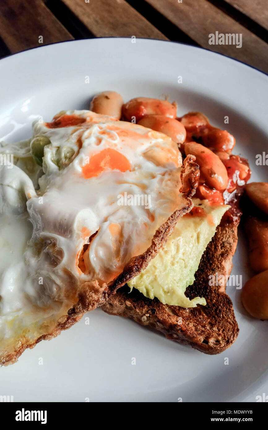 Uovo fritto, avocado e fagioli su pane tostato Foto Stock