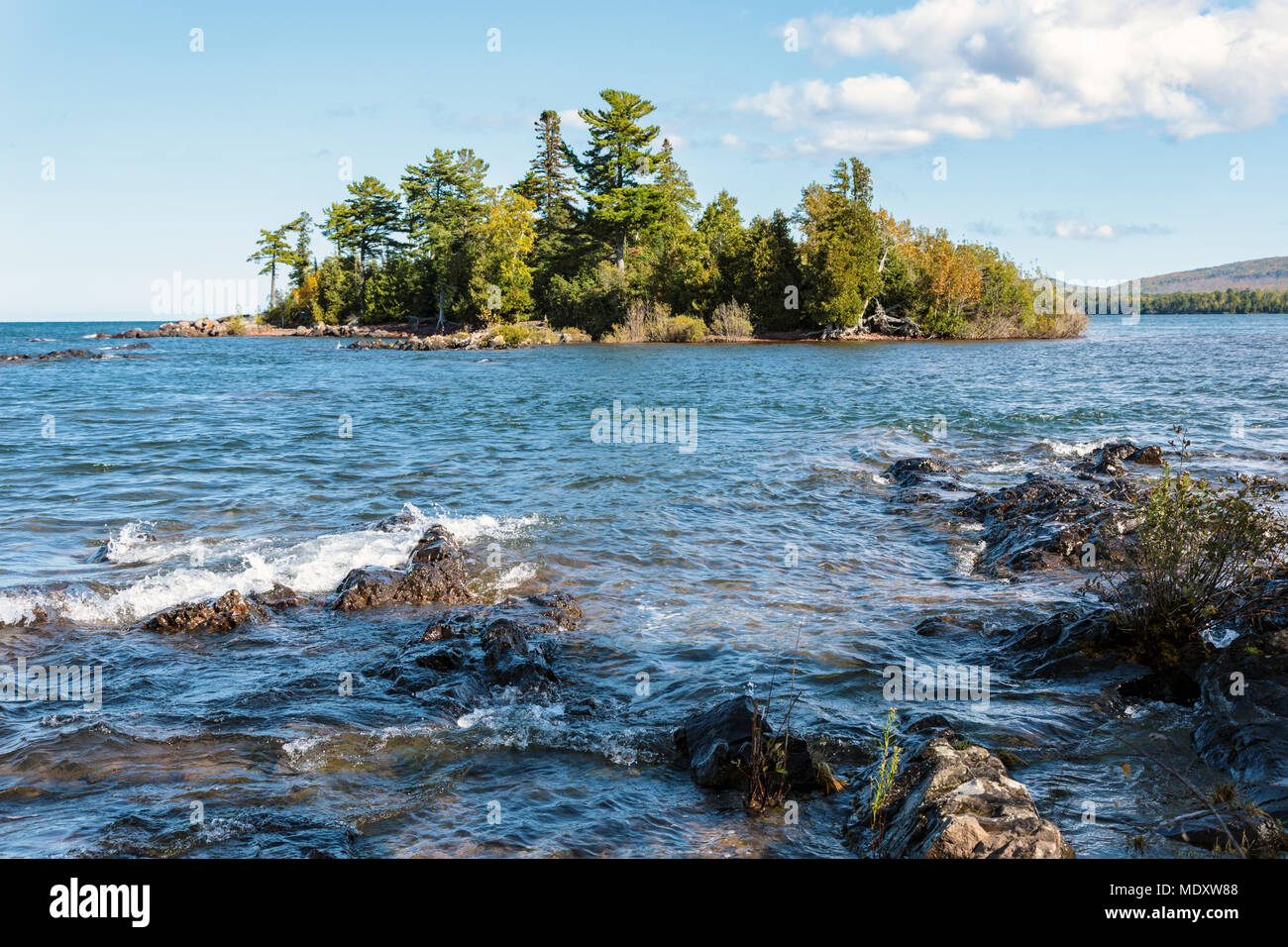 Il chiaro, acque blu del lago Superior circondano il Porter's Island al Porto di rame nel Michigan della penisola Keweenaw. Nuvole bianche e blu cielo Foto Stock