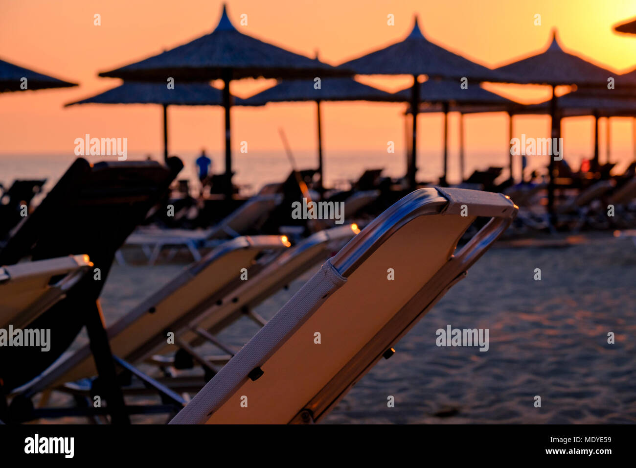 Beach resort con molti ombrelloni reed nel caldo arancio luce del tramonto Foto Stock