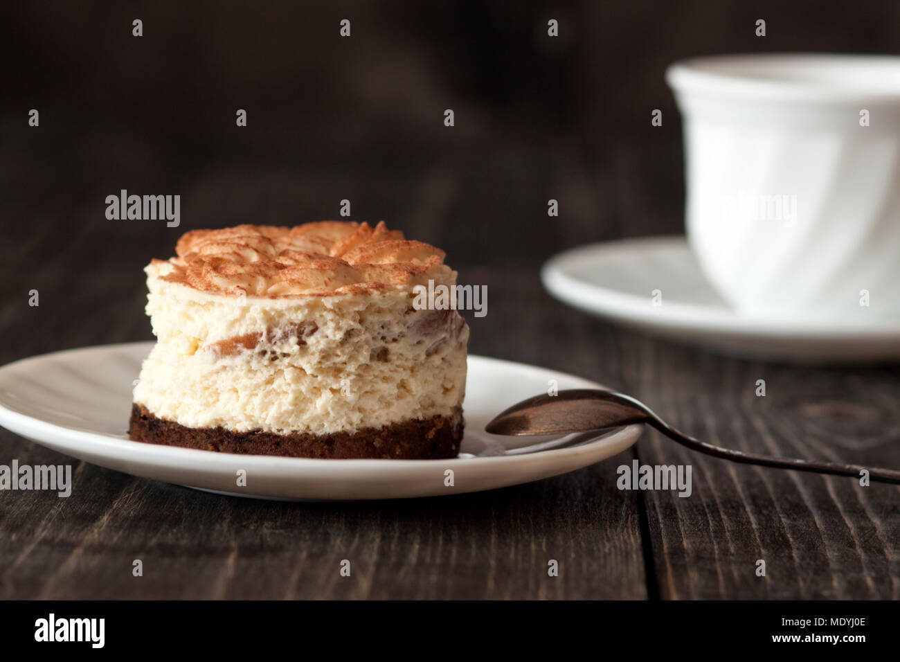 Il tiramisù la torta su un piattino bianco e una tazza di caffè nero Foto Stock