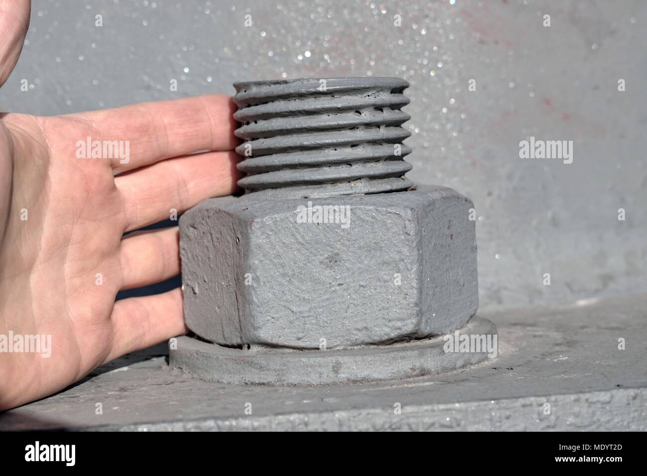 Technology,l'ingegneria,la modernità e il progresso della costruzione del concetto: grandi vite di metallo che fissano un valore di tensione alto pole,confronto con la mano di un uomo. Foto Stock