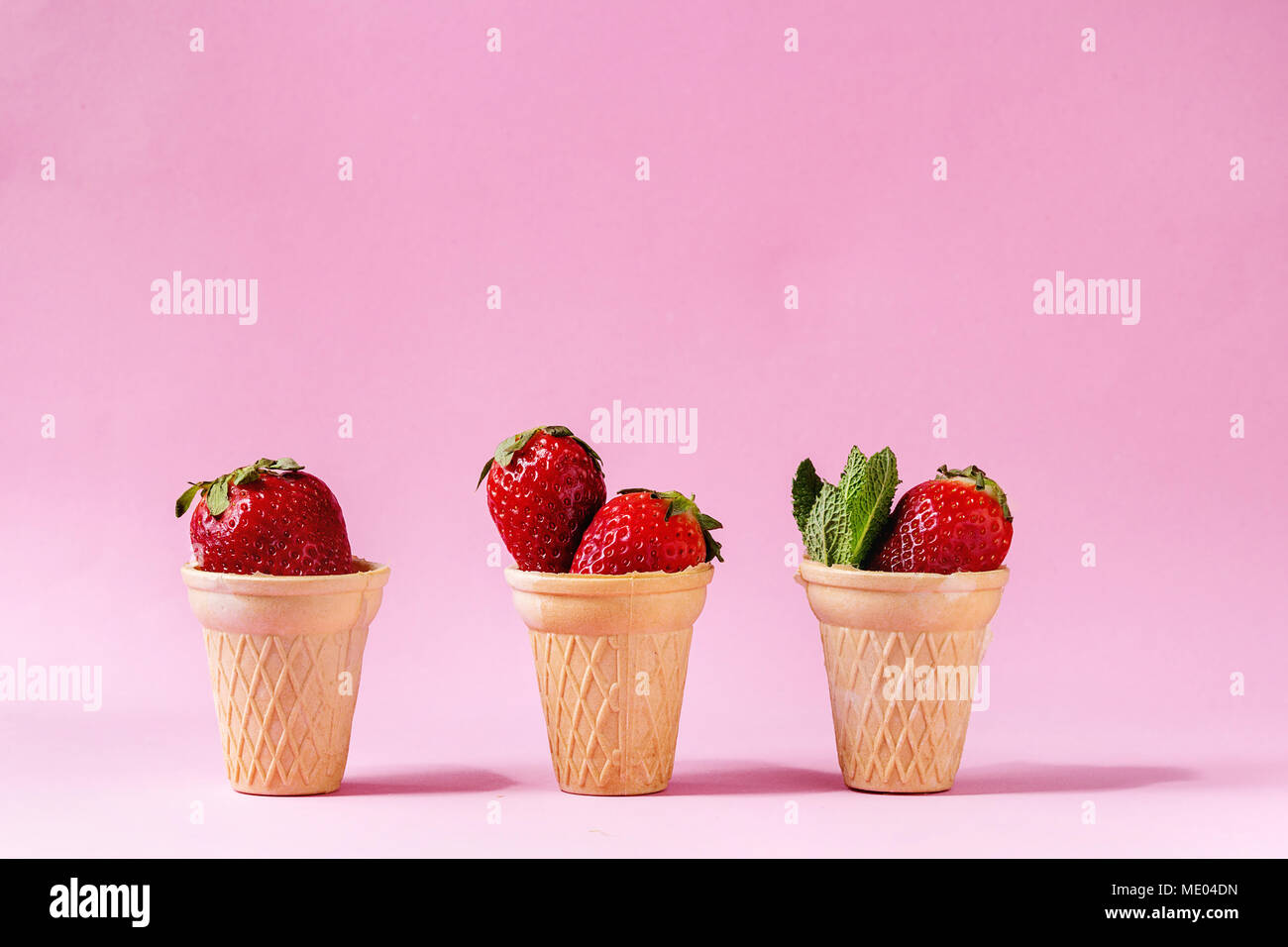 Fragole fresche in tazze waffle su rosa pastello pin-up dello sfondo. Copia dello spazio. Foto Stock