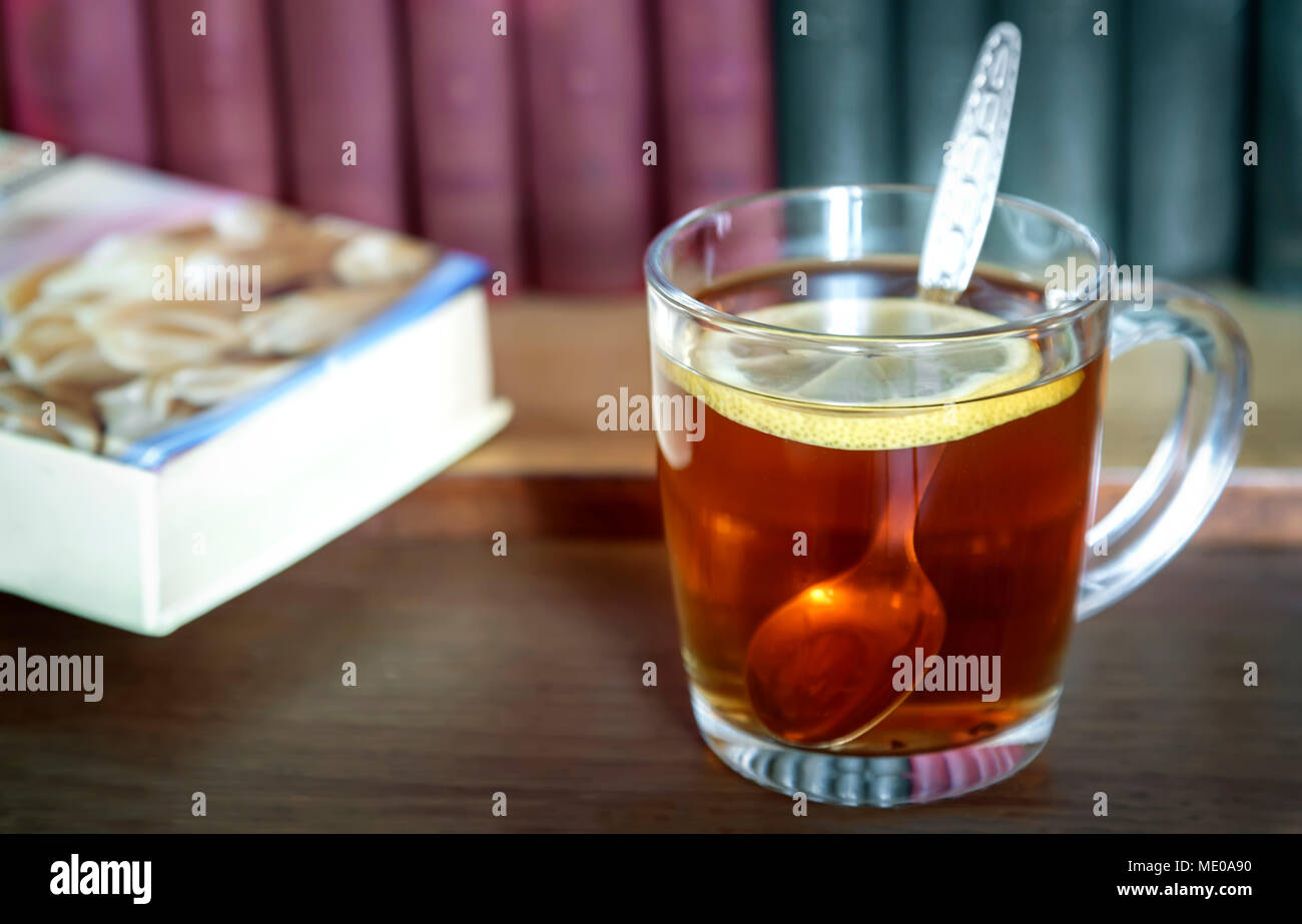 Sul tavolo accanto ai libri è una tazza di tè con il limone. Foto Stock