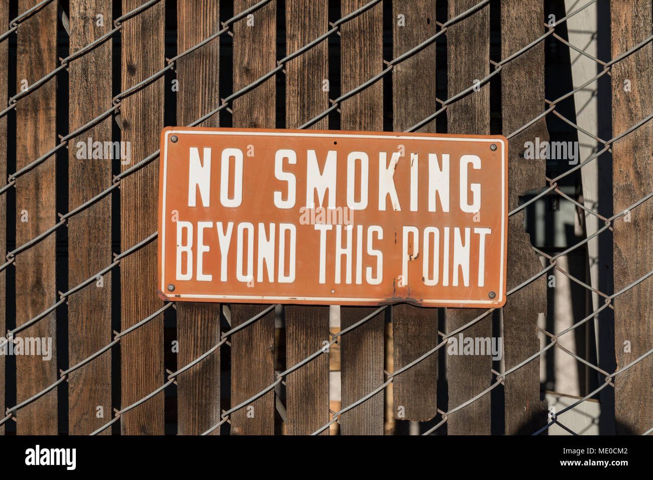 "Vietato fumare oltre questo punto' segno su una recinzione Foto Stock