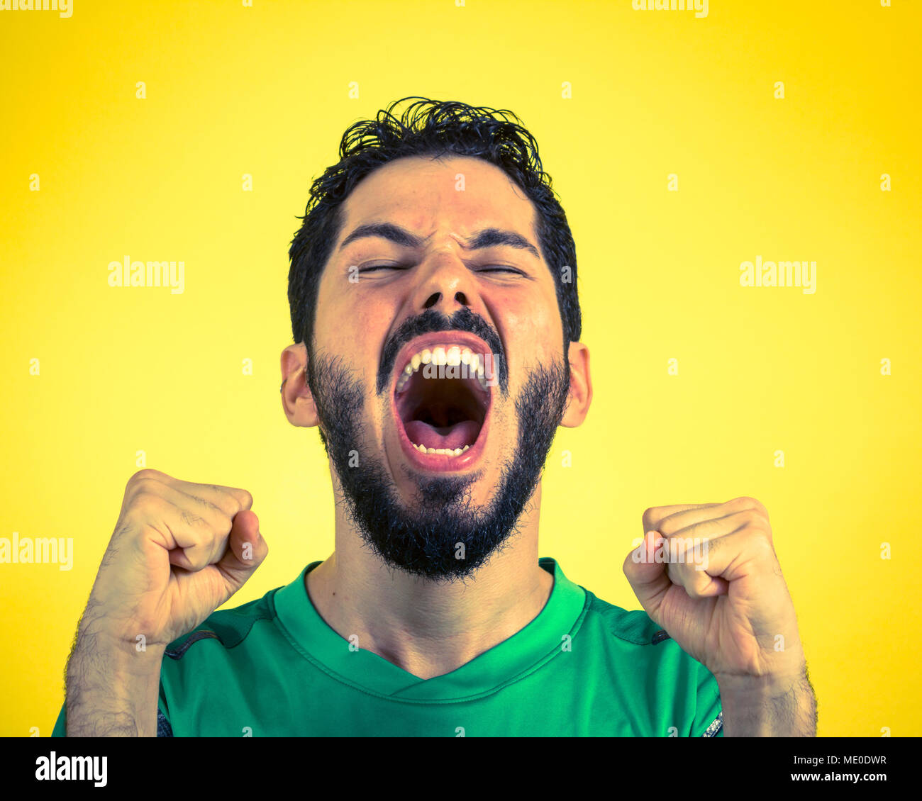 Calcio brasiliano atleta di calcio. Un supporter della ventola e celebrare su sfondo giallo che indossa il verde uniforme. Foto Stock