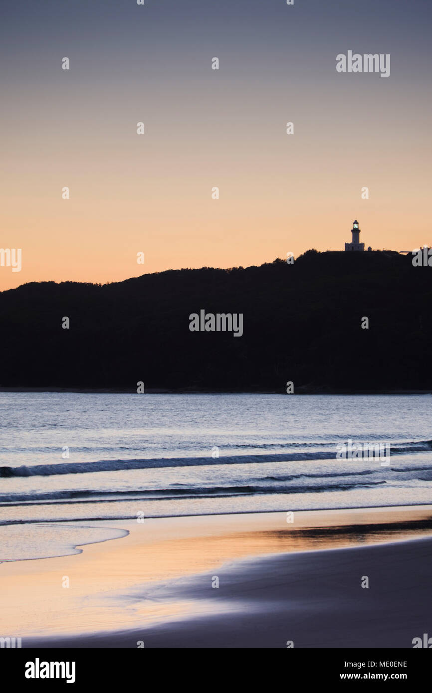 Silhouette di Faro di Cape Byron sulla collina e sulla spiaggia al tramonto a Byron Bay nel Nuovo Galles del Sud, Australia Foto Stock