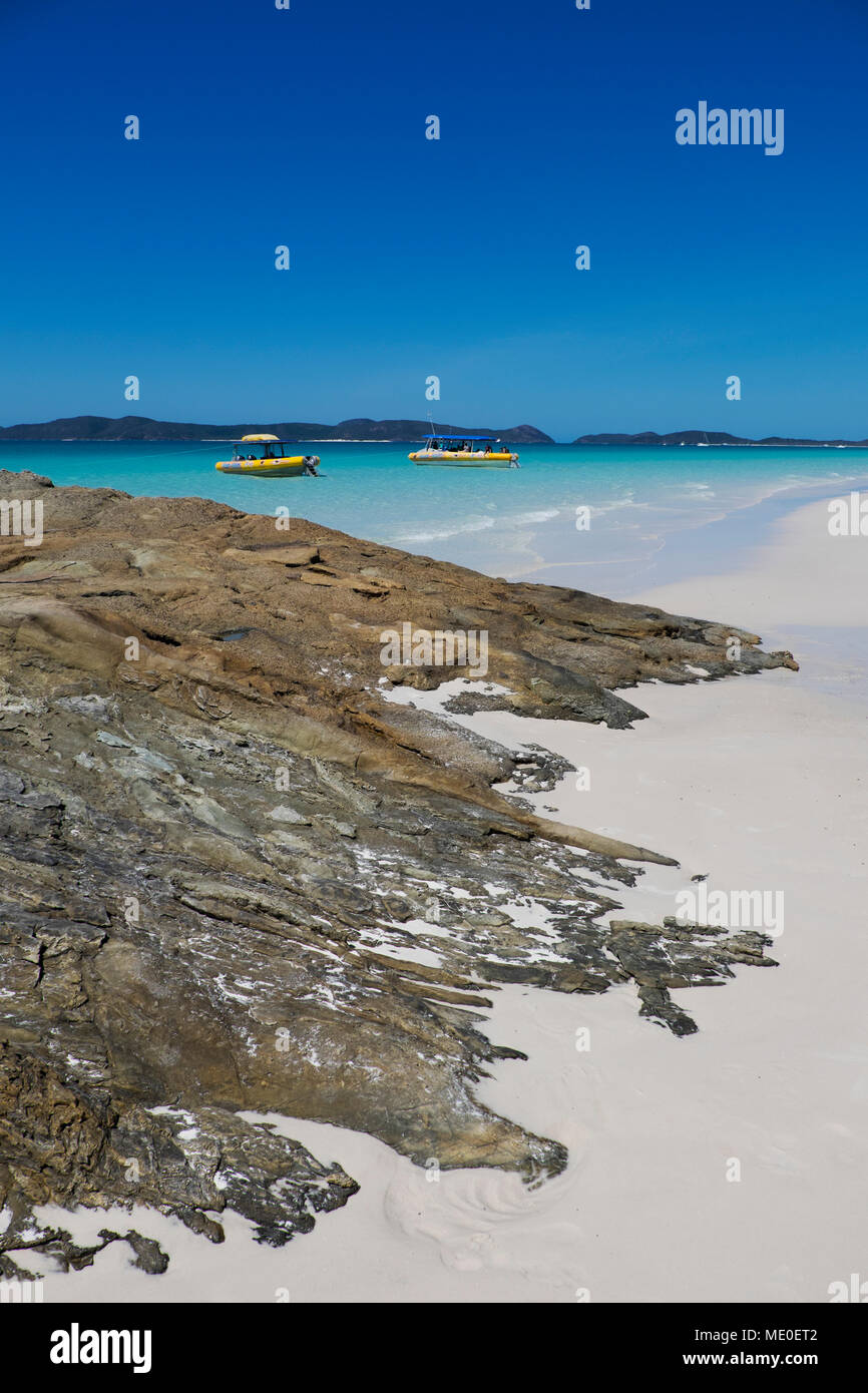 Formazioni di roccia e sabbia bianca sulla Whitehaven Beach con barche ancorate lungo Whitsunday Islands nel Queensland, Australia Foto Stock