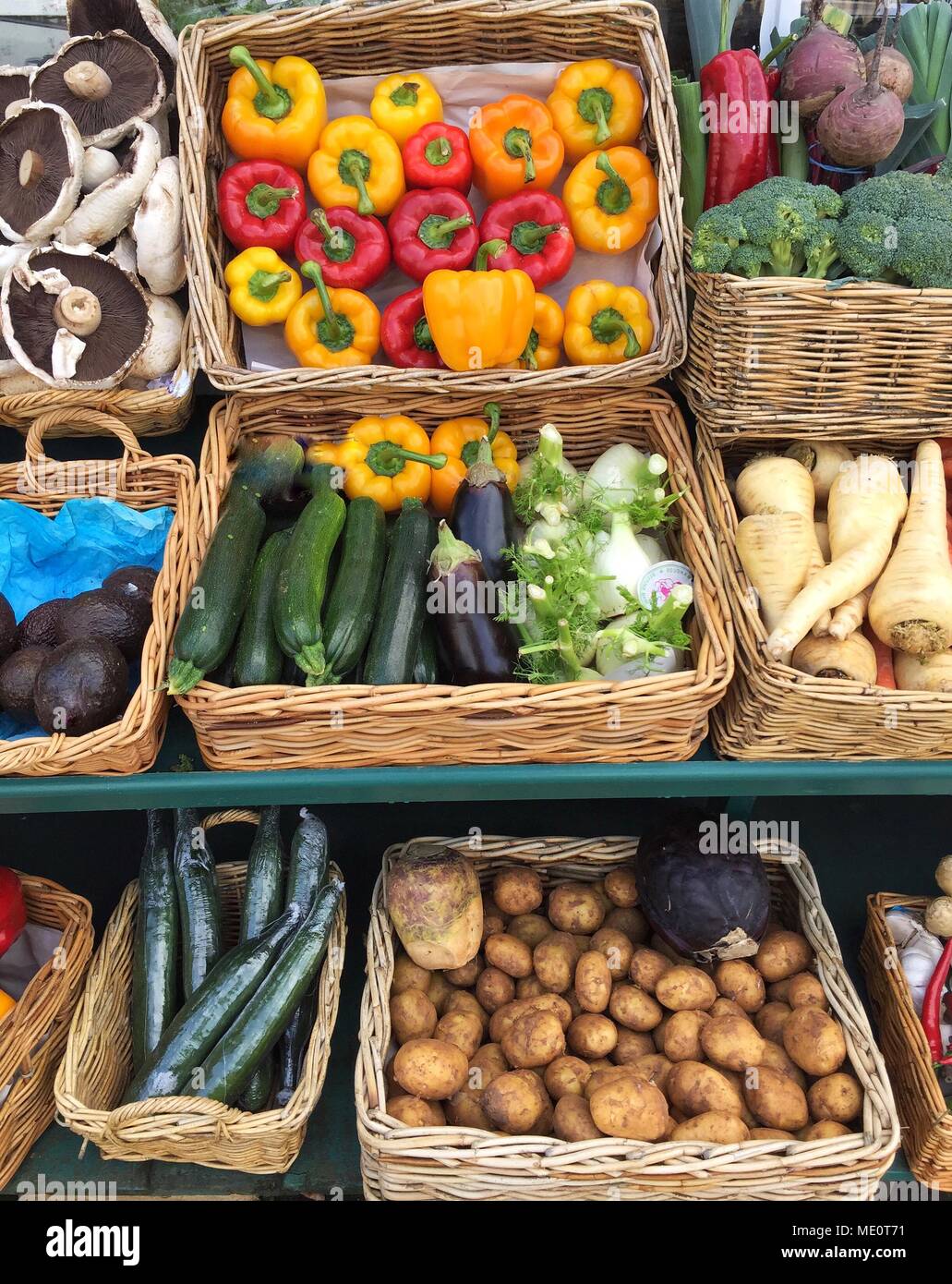 Un mercato all'aperto a carico di stallo con una varietà di carni, frutta e ortaggi con pomodori, funghi e peperoni. Foto Stock