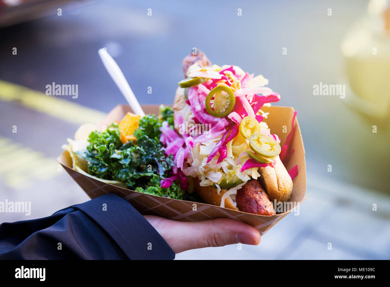 L'uomo azienda vegano cibo di strada nella sua mano destra su un mercato di Brooklyn, a New York City Foto Stock