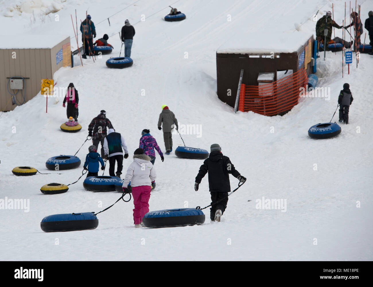 I bambini e i genitori a piedi per il sollevamento del tubo al Hillberg Ski Area durante il Winterfest a base comune Elmendorf-Richardson, Alaska, 21 dicembre 2017. Winterfest era un solstizio d'inverno celebrazione ospitato da Hillberg per chiunque con accesso di base e offerto una pletora di eventi da mezzogiorno al più tardi 8 p.m. (U.S. Air Force foto di Senior Airman Christopher R. Morales) Foto Stock