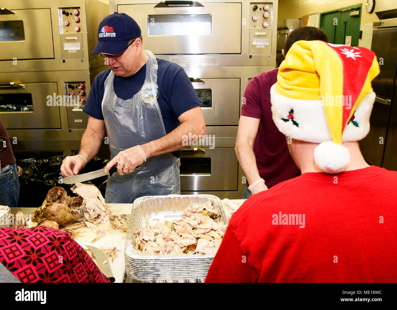 Centoventesimo Airlift Wing comando Master Chief Sgt. Steven Lynch intaglia una Turchia presso il centoventesimo Airlift Wing Dining Facility a Great Falls International Airport a Great Falls, Montana, 24 dic. 2017. Montana Air National Guard il personale si è offerto volontariamente per preparare 50 tacchini, spogliatoio e sugo di carne e consegnato il cibo per il Grande cade il centro anziani di essere servito durante la venticinquesima edizione del Danny Berg Memorial Cena di Natale. (U.S. Air National Guard foto/Senior Master Sgt. Eric Peterson) Foto Stock