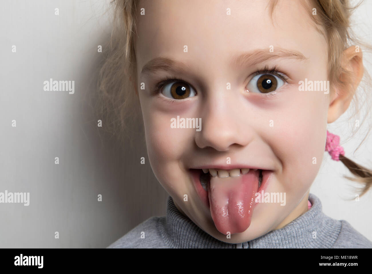 Felice bambina mostrando la sua lingua. Foto Stock