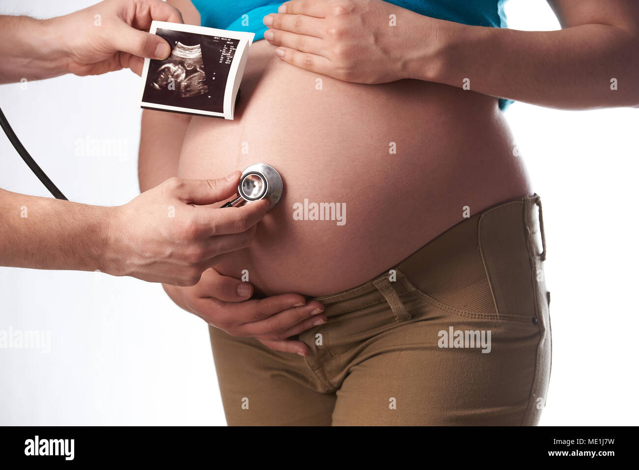 Controllare la donna incinta ventre con uno stetoscopio isolati su sfondo bianco Foto Stock
