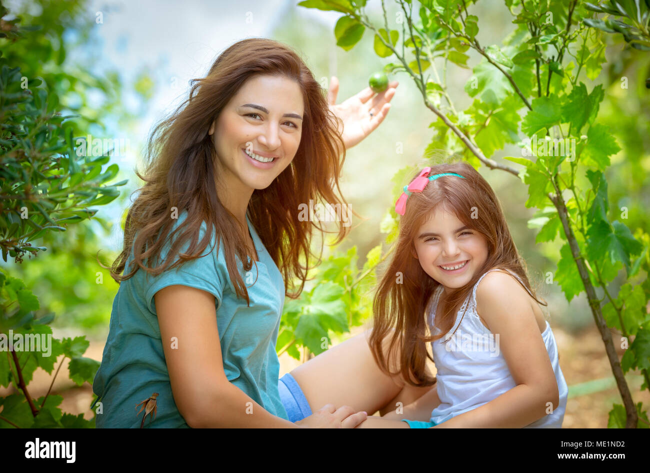 Madre e figlia nel frutteto, godendo la comparsa dei primi frutti, giovani giardinieri con piacere di trascorrere del tempo in giardino, vita felice in Foto Stock