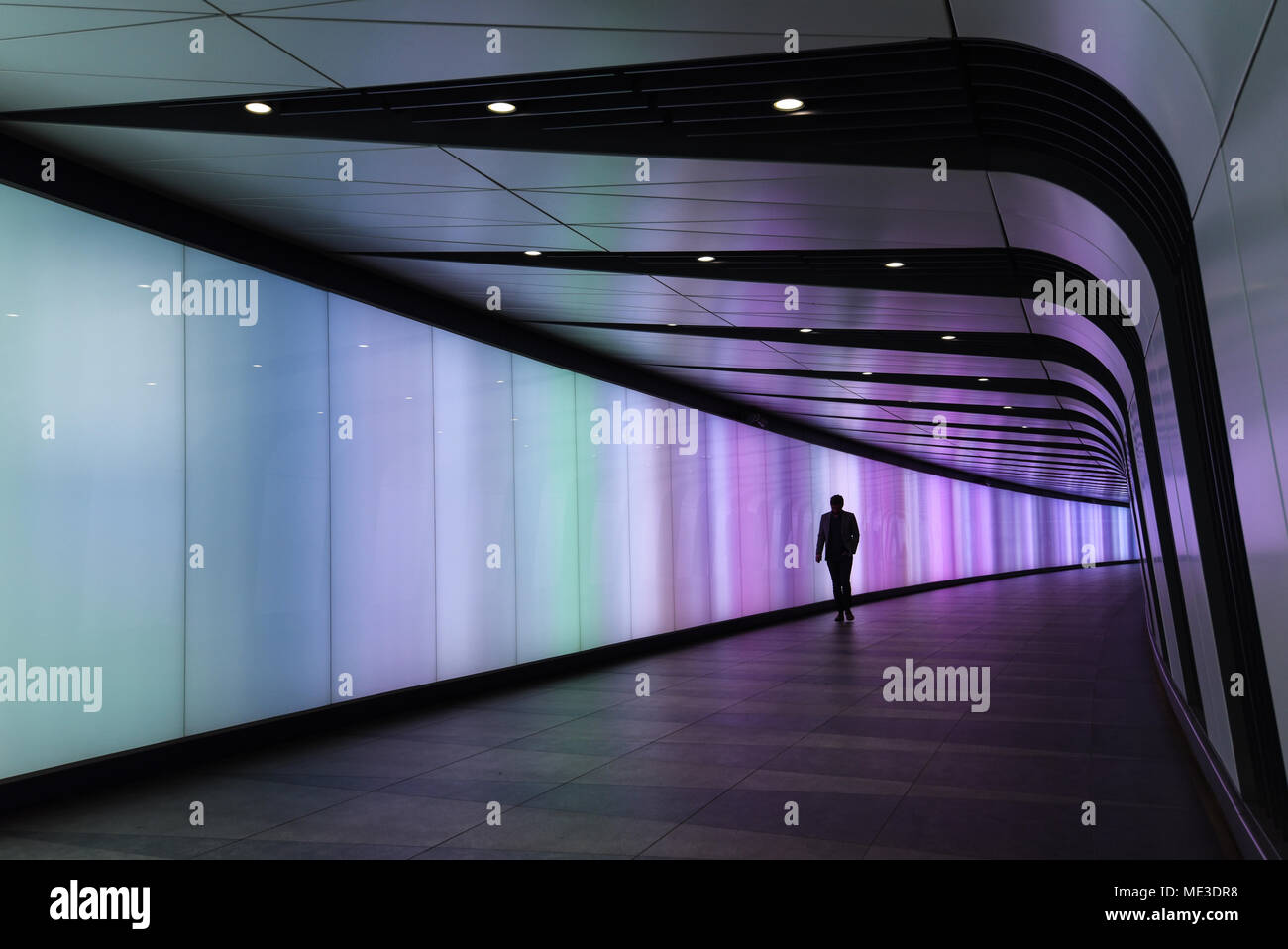 Stagliano uomo a camminare attraverso il tunnel illuminato Foto Stock