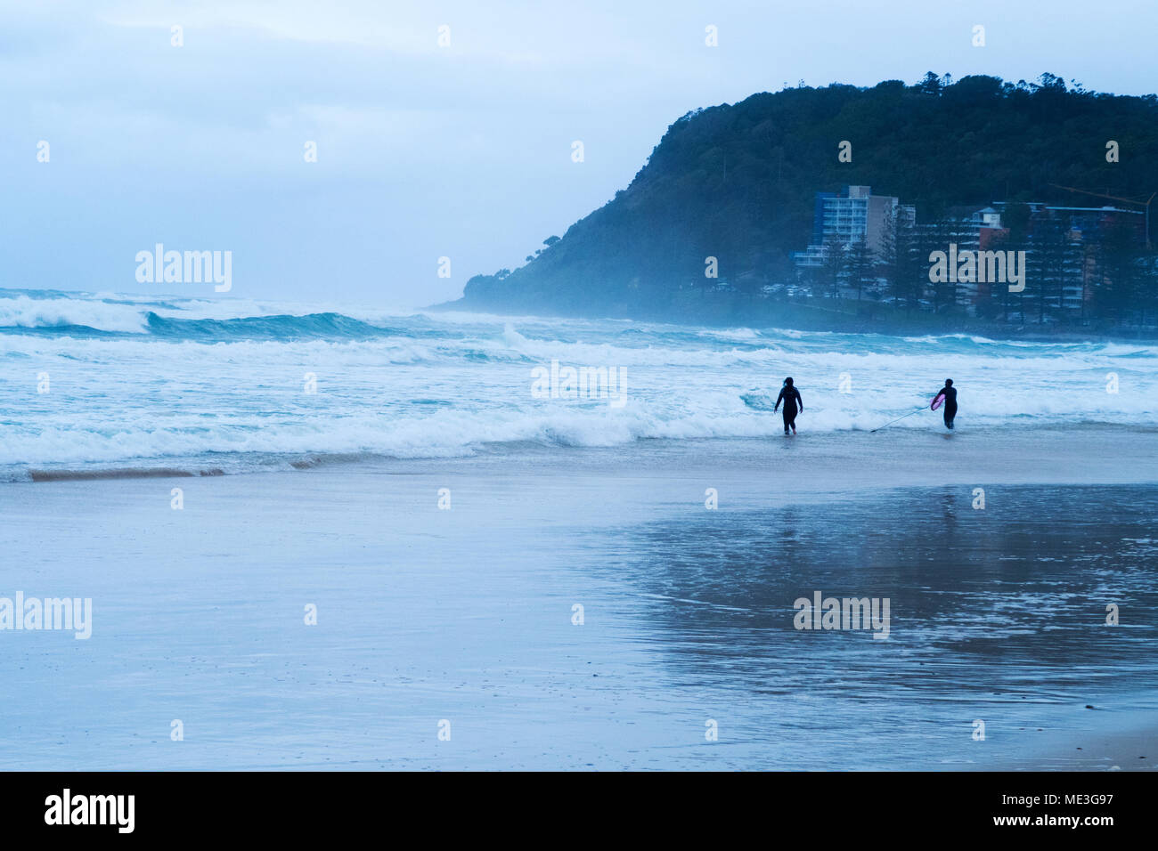 Surfers che entra in mare durante una tempesta di Burleigh capi sulla Gold Coast in Australia Foto Stock