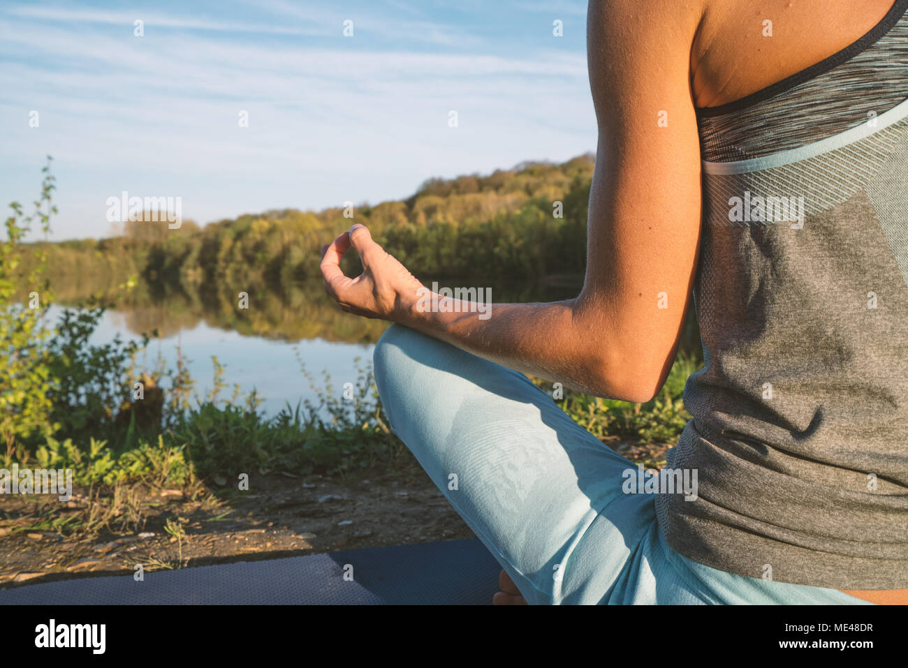 Giovane donna esercizio di yoga in riva al lago al tramonto, persone Viaggi natura benessere e relax concetto. Girato in Francia, l'Europa. Lotus pongono Foto Stock