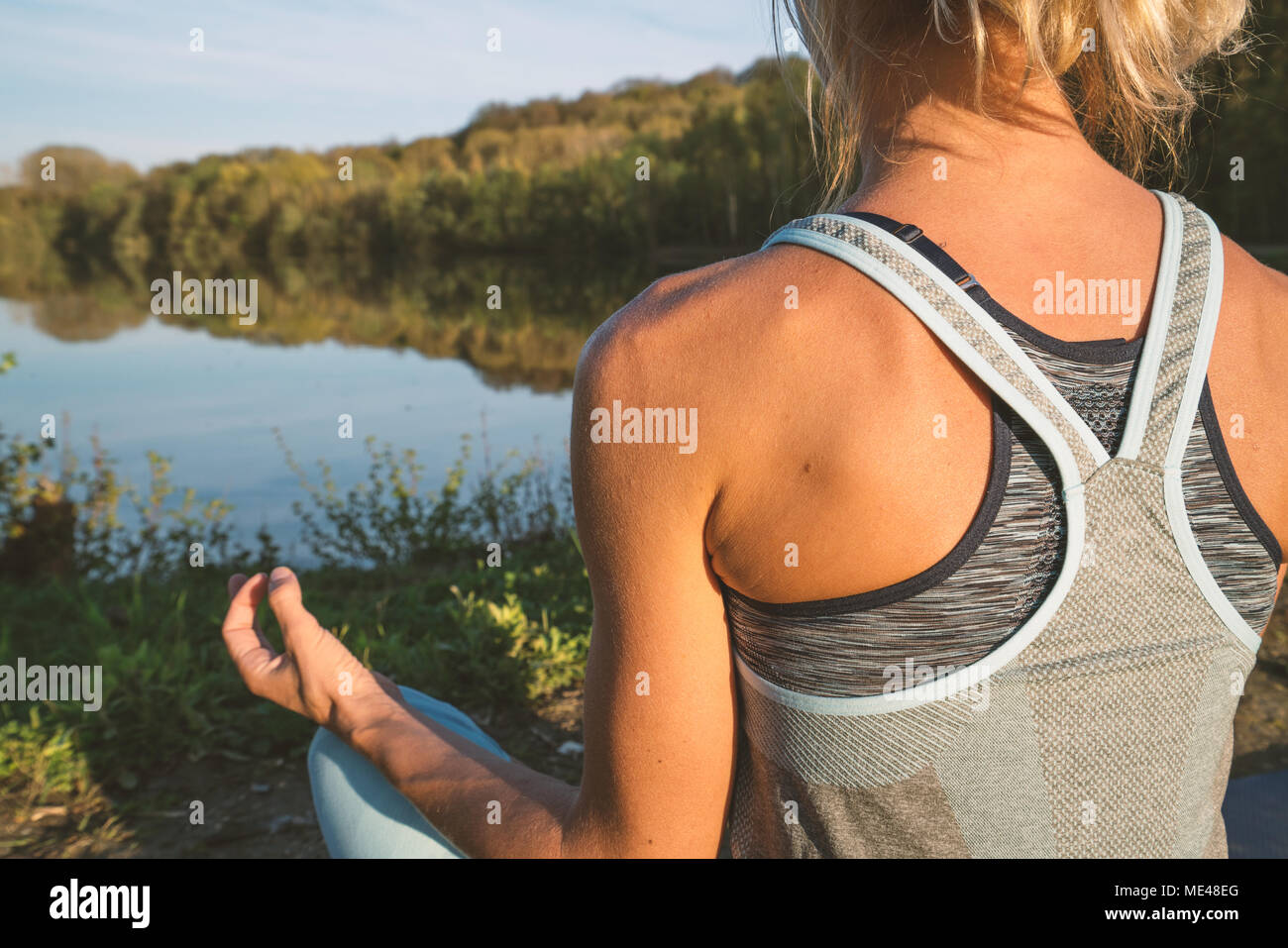 Giovane donna esercizio di yoga in riva al lago al tramonto, persone Viaggi natura benessere e relax concetto. Girato in Francia, l'Europa. Lotus pongono Foto Stock