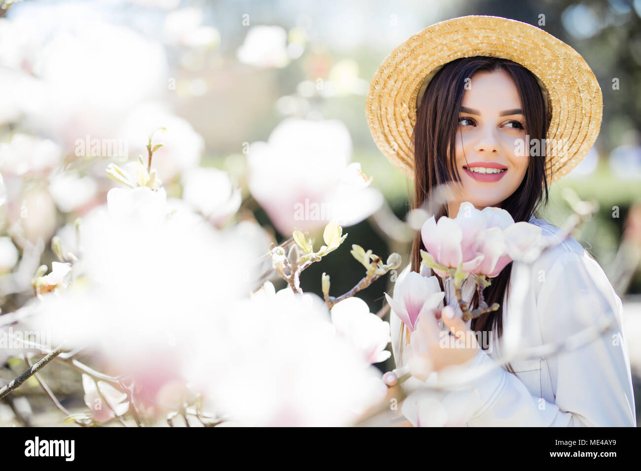 Outdoor Ritratto di giovane donna bellissima vicino albero di magnolia con fiori. Foto Stock