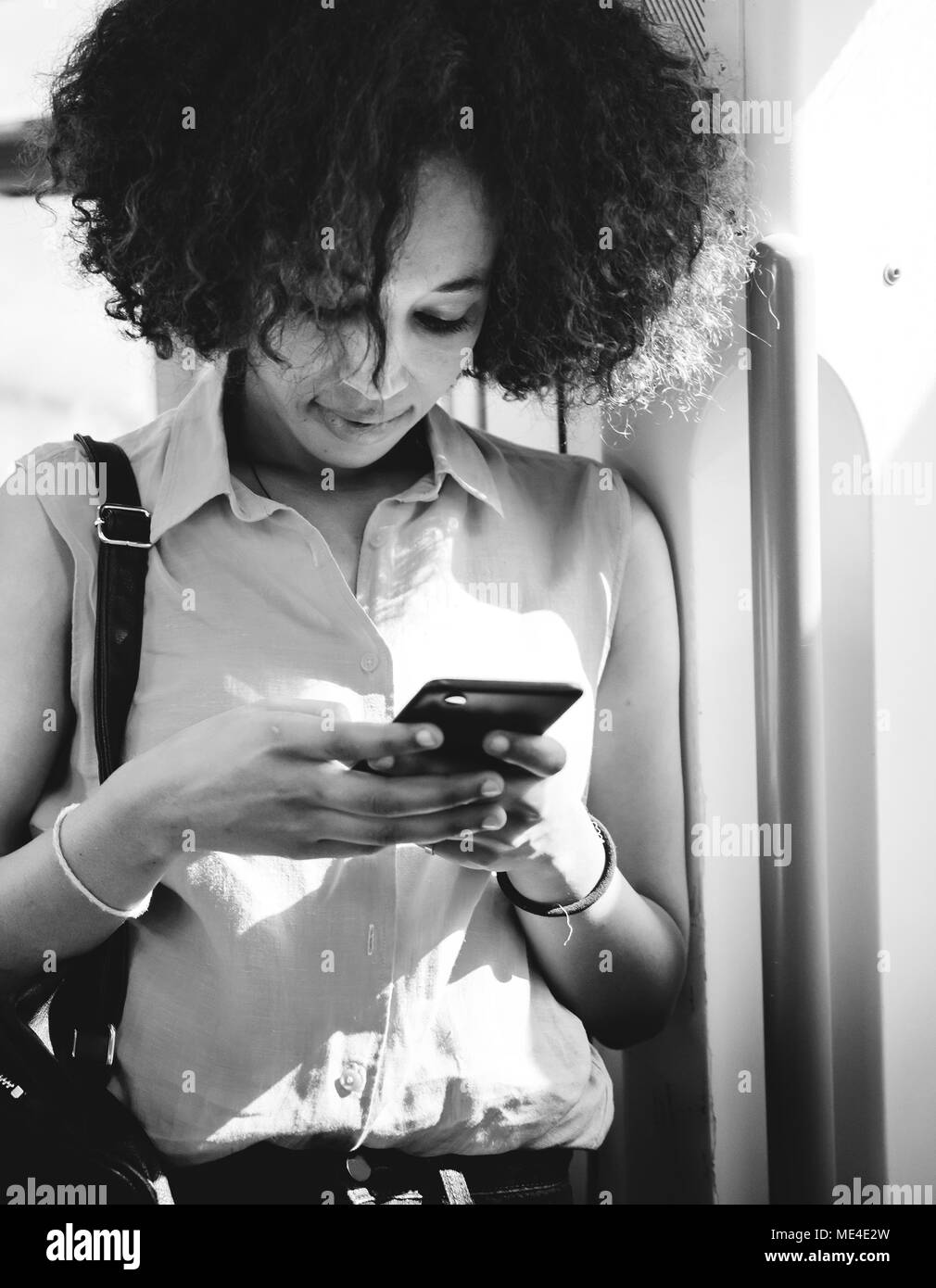 Giovane donna utilizzando uno smartphone in metropolitana Foto Stock