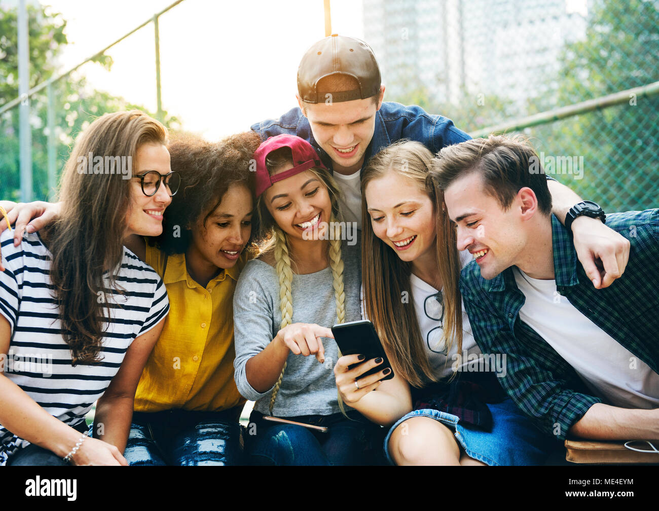 Amici nel parco cercando utilizzando gli smartphone e la millenaria cultura giovanile concept Foto Stock