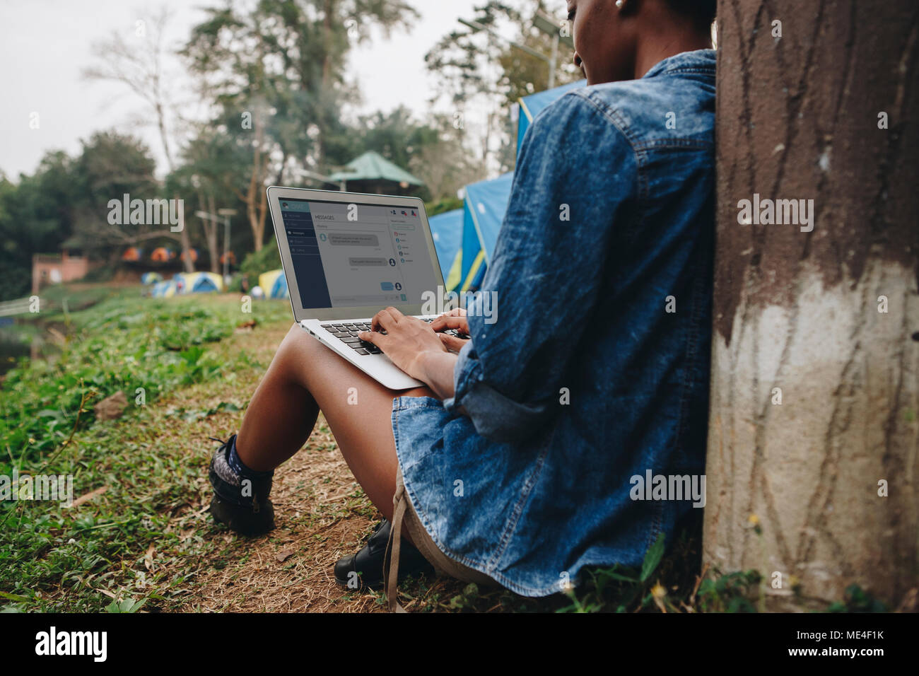 La donna da soli in natura utilizzando un computer portatile su un campeggio via di fuga dal lavoro o la dipendenza da internet concept Foto Stock
