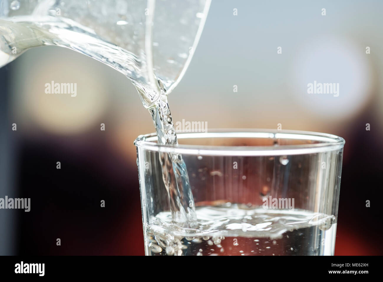 Macro shot di versare acqua in un bicchiere Foto Stock