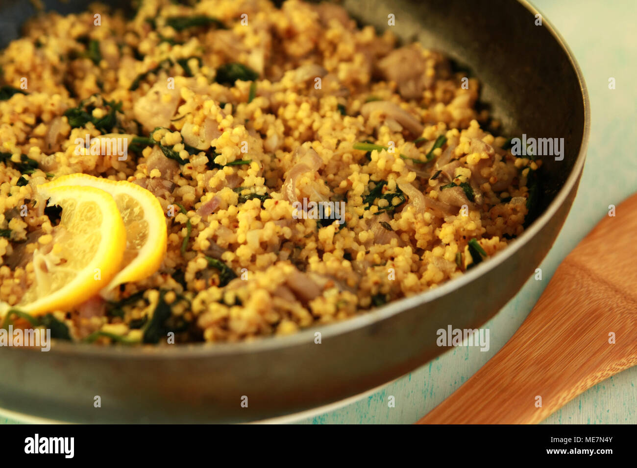 Il cous cous vegetariano con funghi e spinaci. Piatto vegano con miglio in padella. Close up. Foto Stock