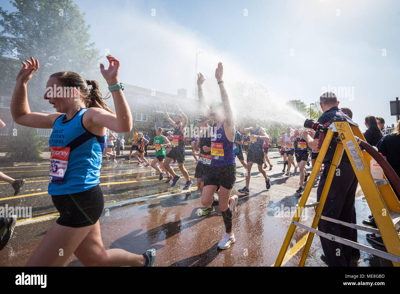 Londra, Regno Unito. Il 22 aprile, 2018. Deptford fire station offre tanto bisogno di raffreddamento ad acqua utilizzando le loro manichette da incendio come corridori della trentottesima London Marathon passa attraverso Deptford su una delle più calde di maratona su record. Le temperature sono attesi al picco a 23C (73,4 F).Credit: Guy Corbishley/Alamy Live News Foto Stock