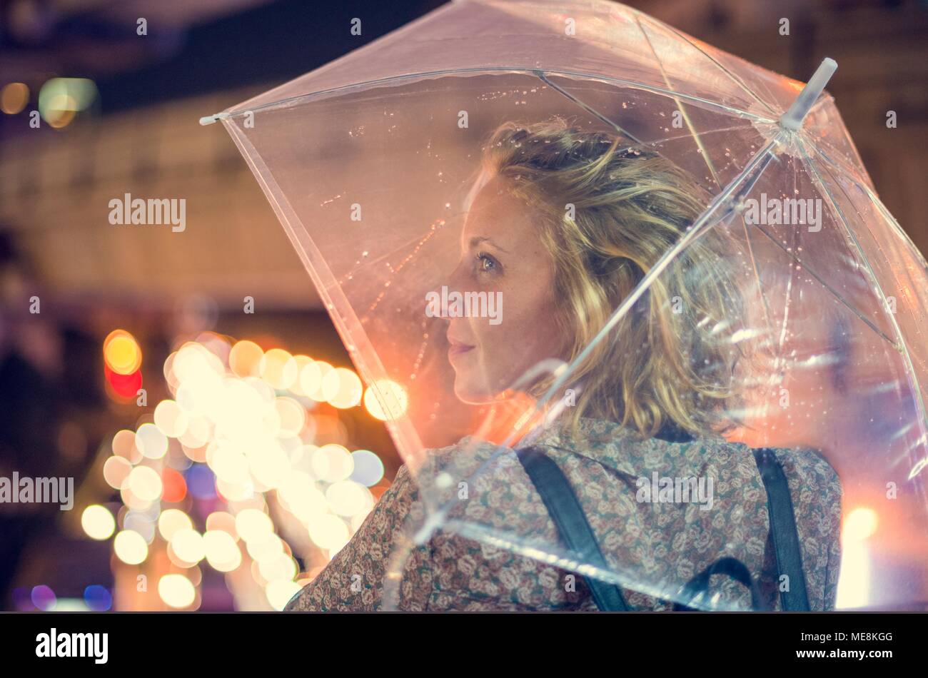 Donna bionda tenendo il coperchio sotto il suo ombrello Foto Stock