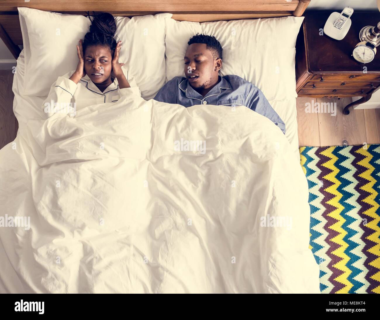 African American giovane sul letto, l'uomo il russamento e disturbi la donna's dormire Foto Stock