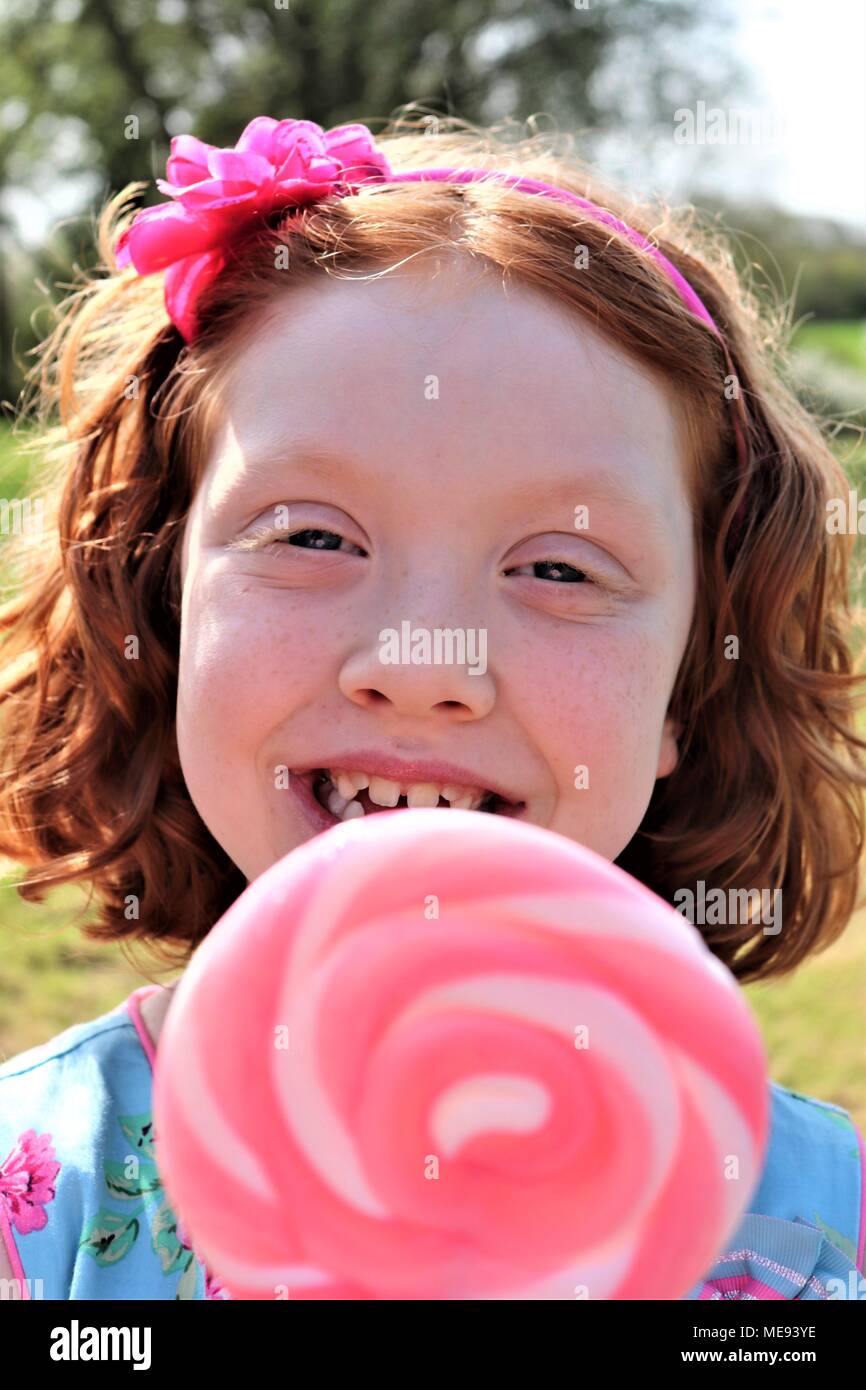 Lo zenzero Una ragazza dai capelli in un bel vestito blu con una grande rosa e bianco lecca-lecca Foto Stock