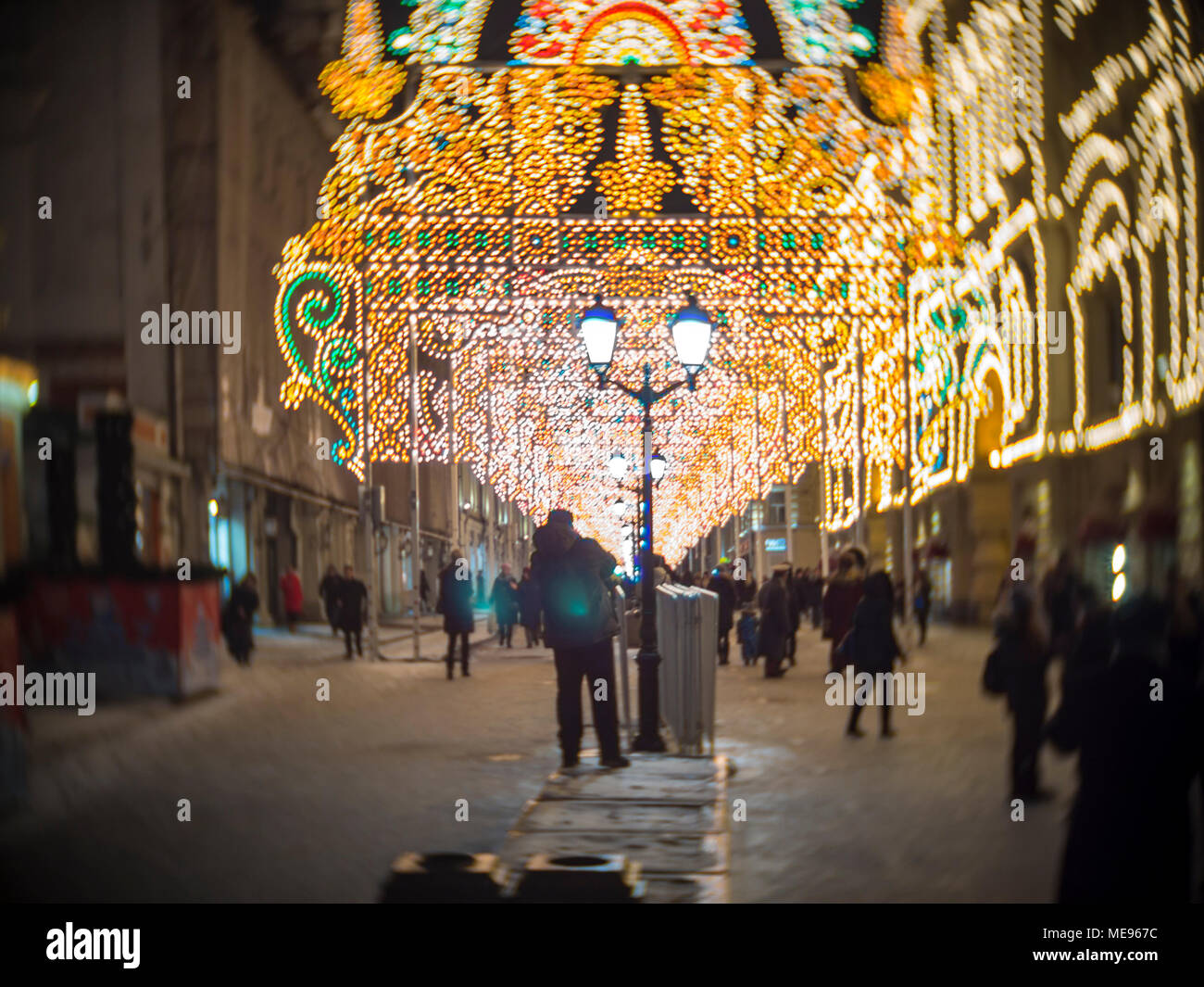 La gente a piedi lungo la strada di notte con una decorazione di luci luminose in inverno a Mosca Foto Stock