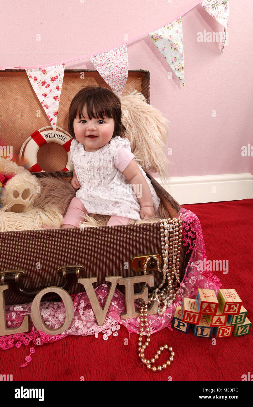 3 mese fa bambina esplorando in vivaio, lo sviluppo cognitivo, giocando in valigia vintage Foto Stock