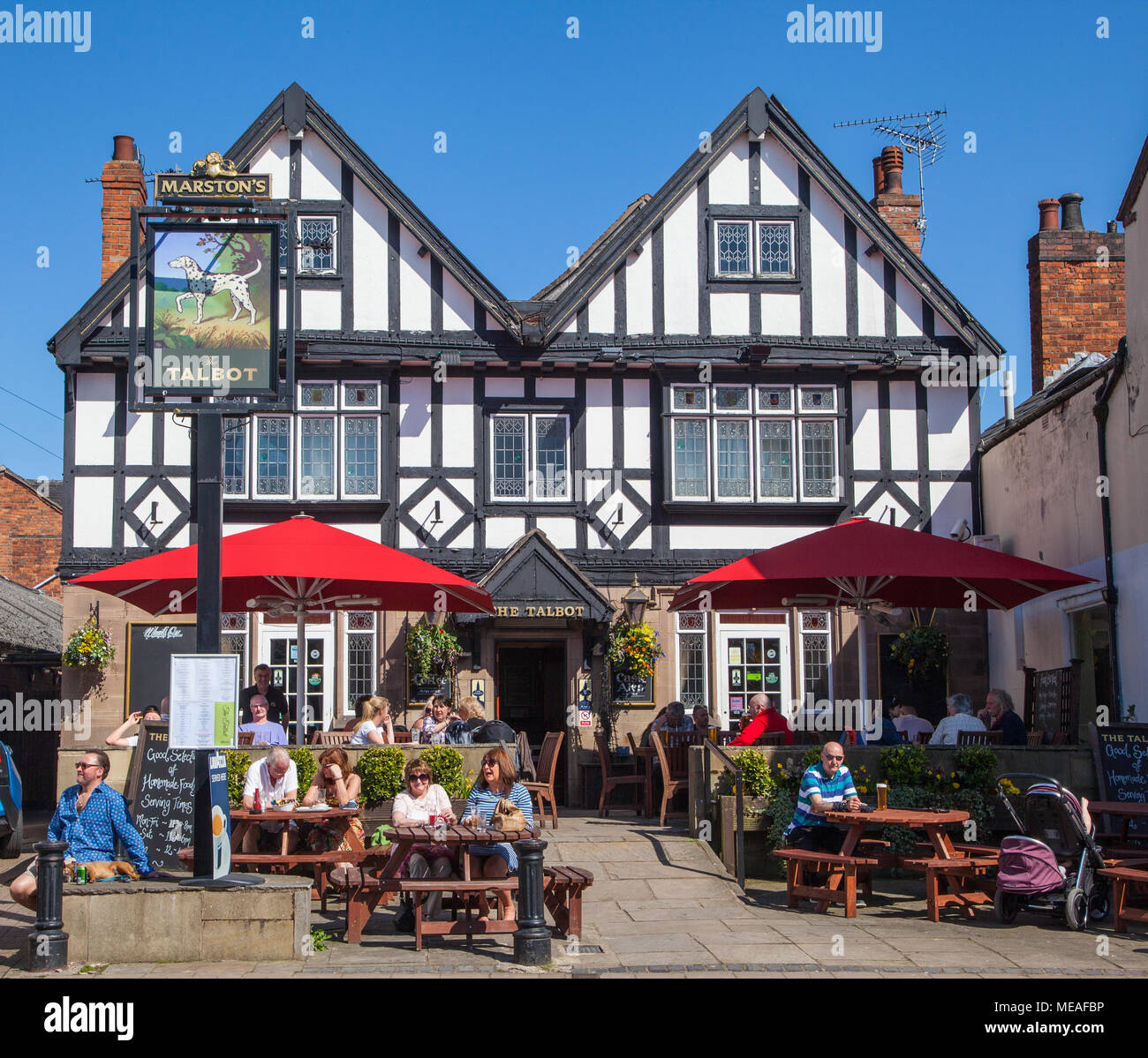 La gente seduta fuori a mangiare e a bere in sole di primavera nel Cheshire città di Nantwich al bianco e nero graticcio Talbot inn Foto Stock