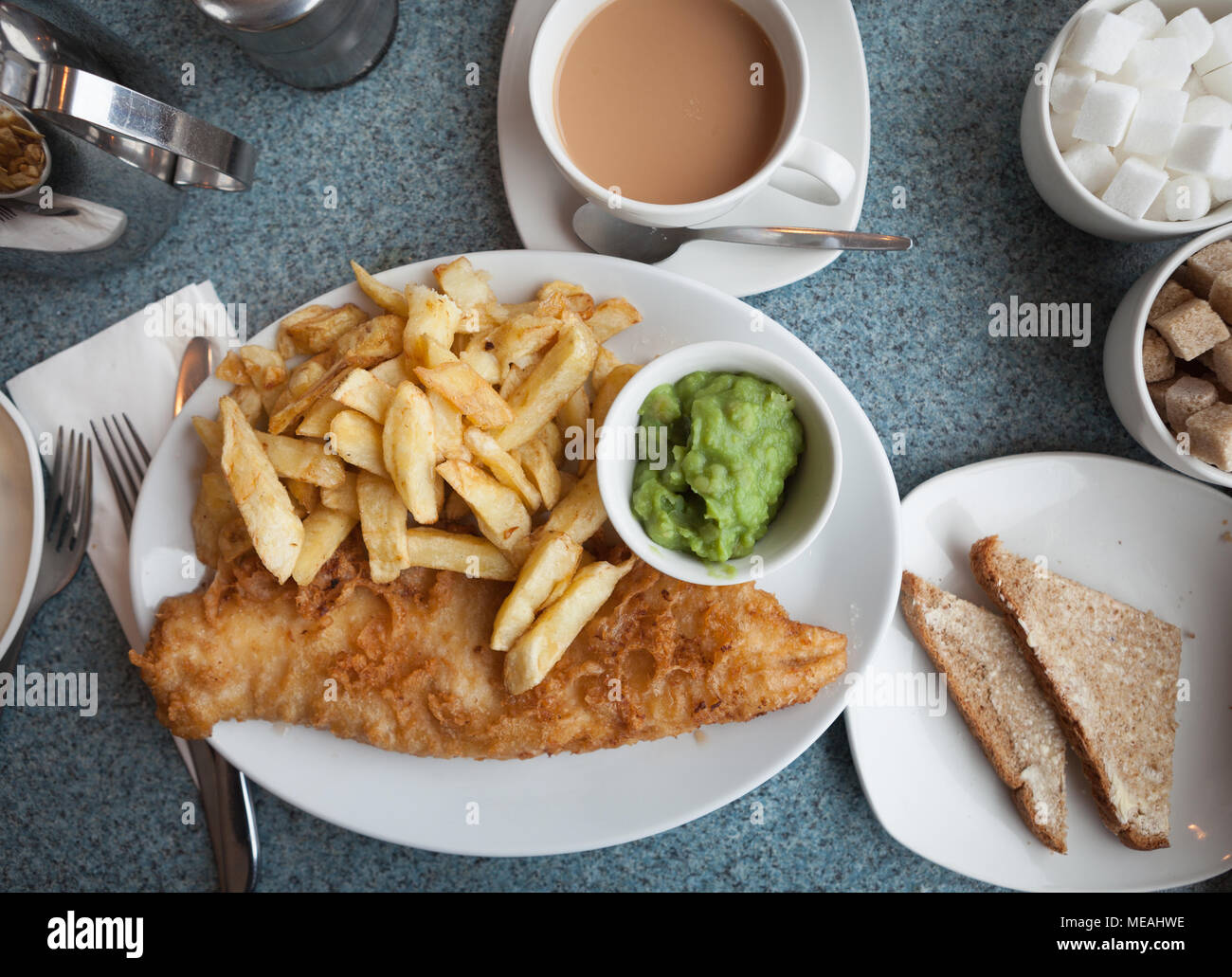 Britannica autentica pesce e patatine, con fiacco piselli, pane imburrato e una tazza di tè Foto Stock