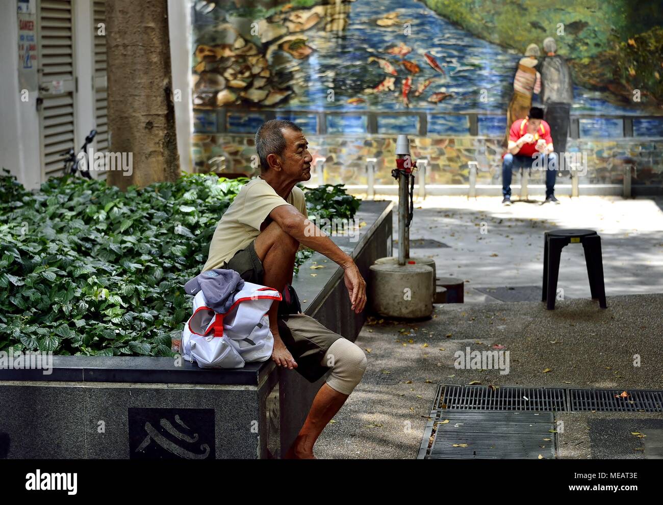 Visualizzazione del profilo di un anziano uomo cinese seduto in un vicolo a Chinatown Foto Stock