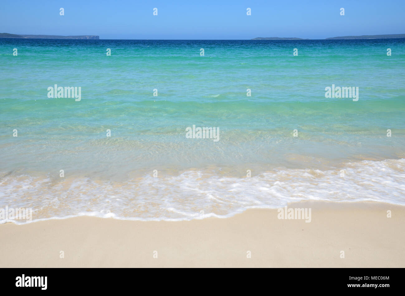 Vista panoramica dalla spiaggia della baia di fronte al promontorio. Beach scene oceano di lappatura sulla spiaggia con acque calme. Foto Stock