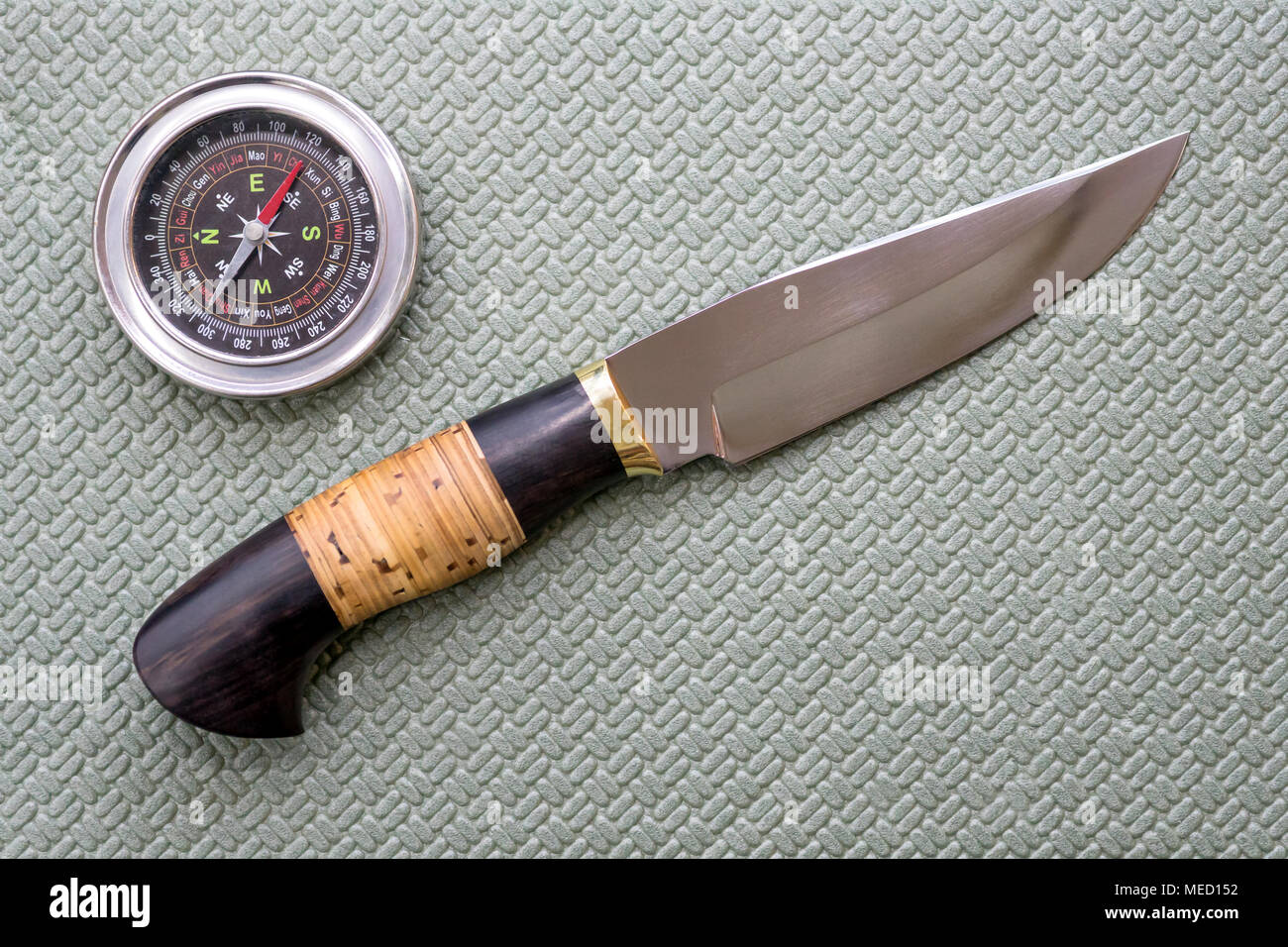 Un coltello da caccia e una bussola giacciono su un tappeto turistica. Attrezzature per il viaggio. Foto Stock