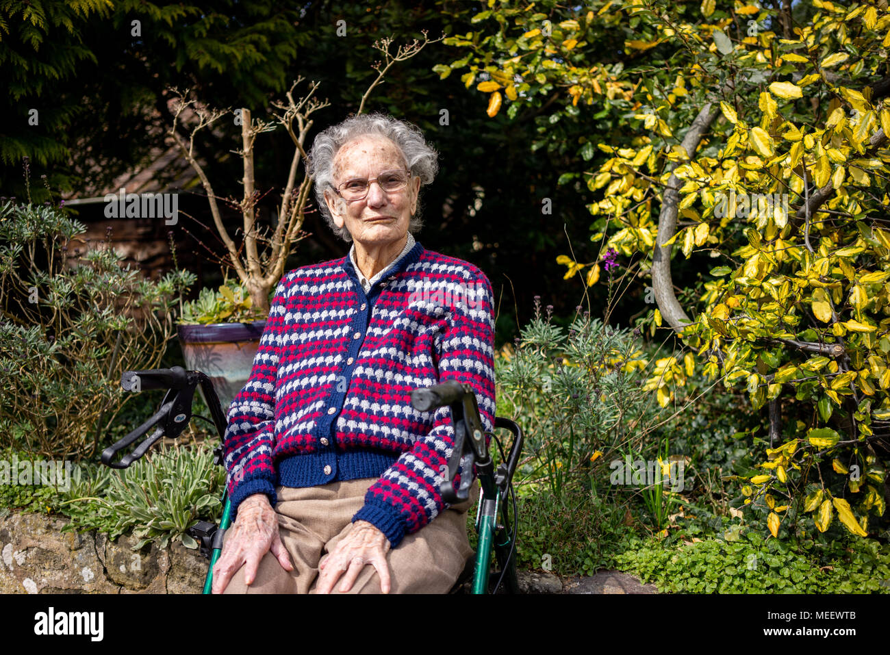 Donna anziana seduta nel suo giardino nel West Sussex England Foto Stock