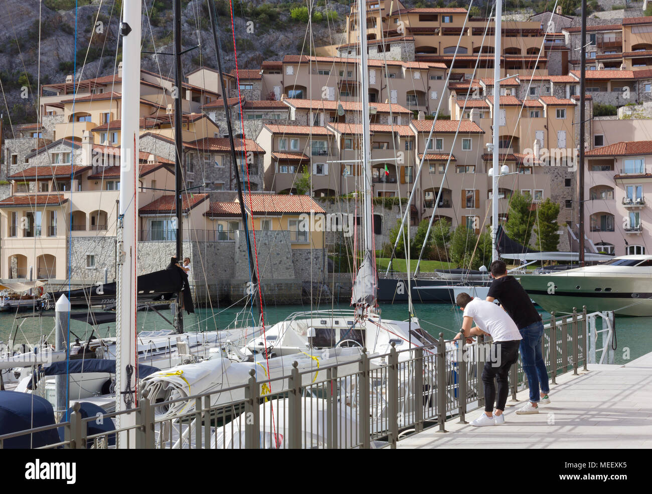 DUINO AURISINA, Italia - 14 Aprile 2018: due ragazzi appoggiati contro una ringhiera presso la marina in Portopicclo, vicino a Trieste, Italia Foto Stock