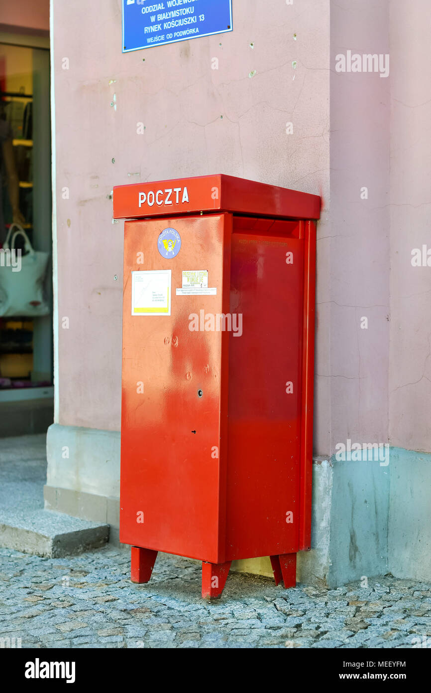 Bialystok, Polonia - 30 Aprile 2012: rosso metallico della cassetta postale nazionale e internazionale polacco di stato del servizio postale si erge a muro sulla pavimentazione in pietra. Lettera Foto Stock