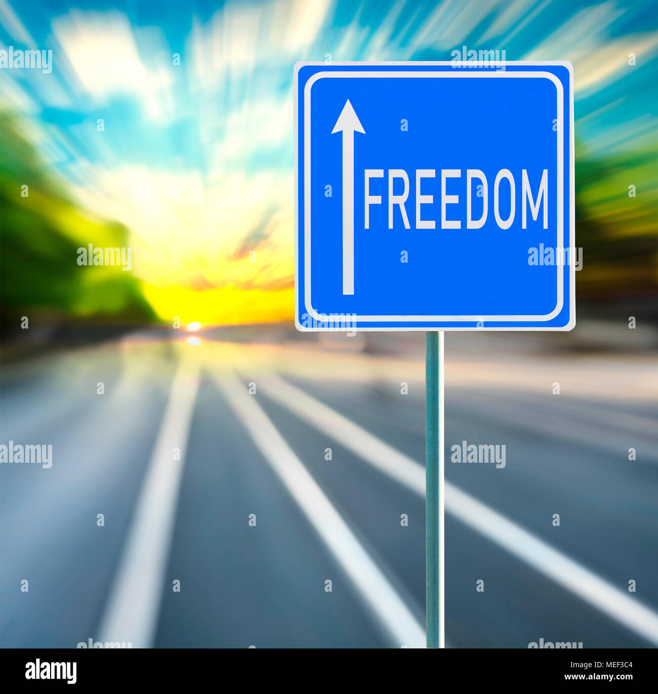Libertà frase motivazionale sul cartello blu con la freccia e sfocata speedy background nel tramonto. Copia dello spazio. Foto Stock