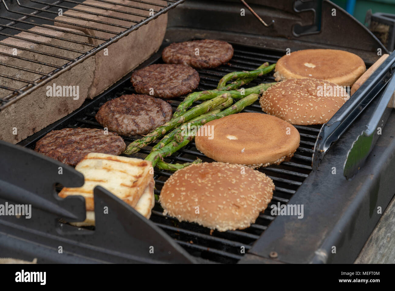 Set di hamburger. La persona che sta andando a griglia polpette di carne, salsicce, formaggio alla griglia e asparagi Foto Stock