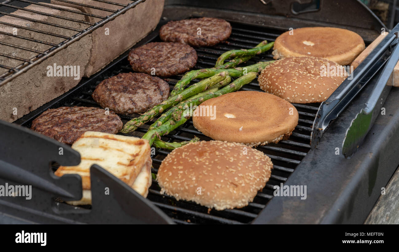 Set di hamburger. La persona che sta andando a griglia polpette di carne, salsicce, formaggio alla griglia e asparagi Foto Stock