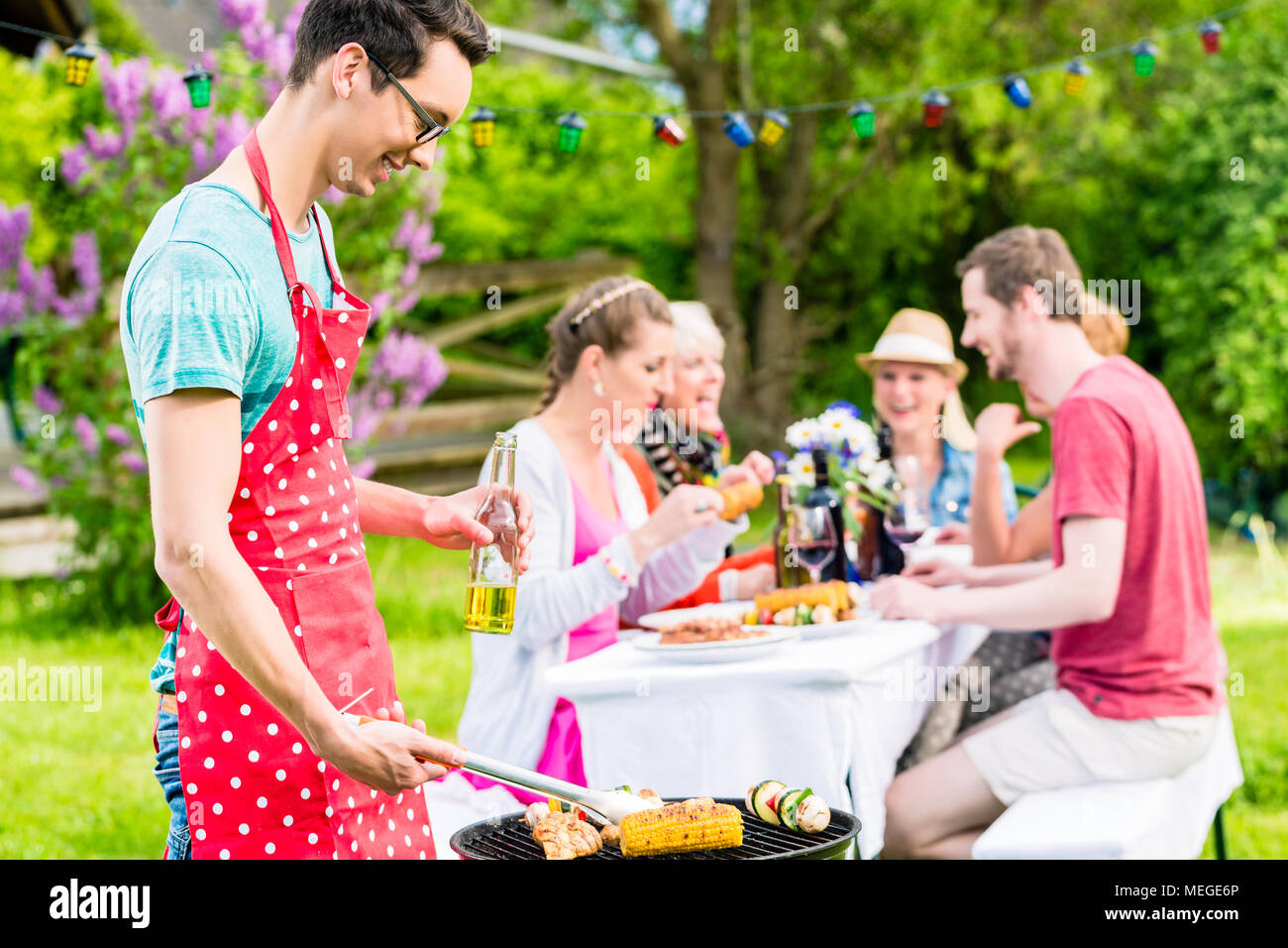 L'uomo cuocere carne sul giardino barbecue party Foto Stock