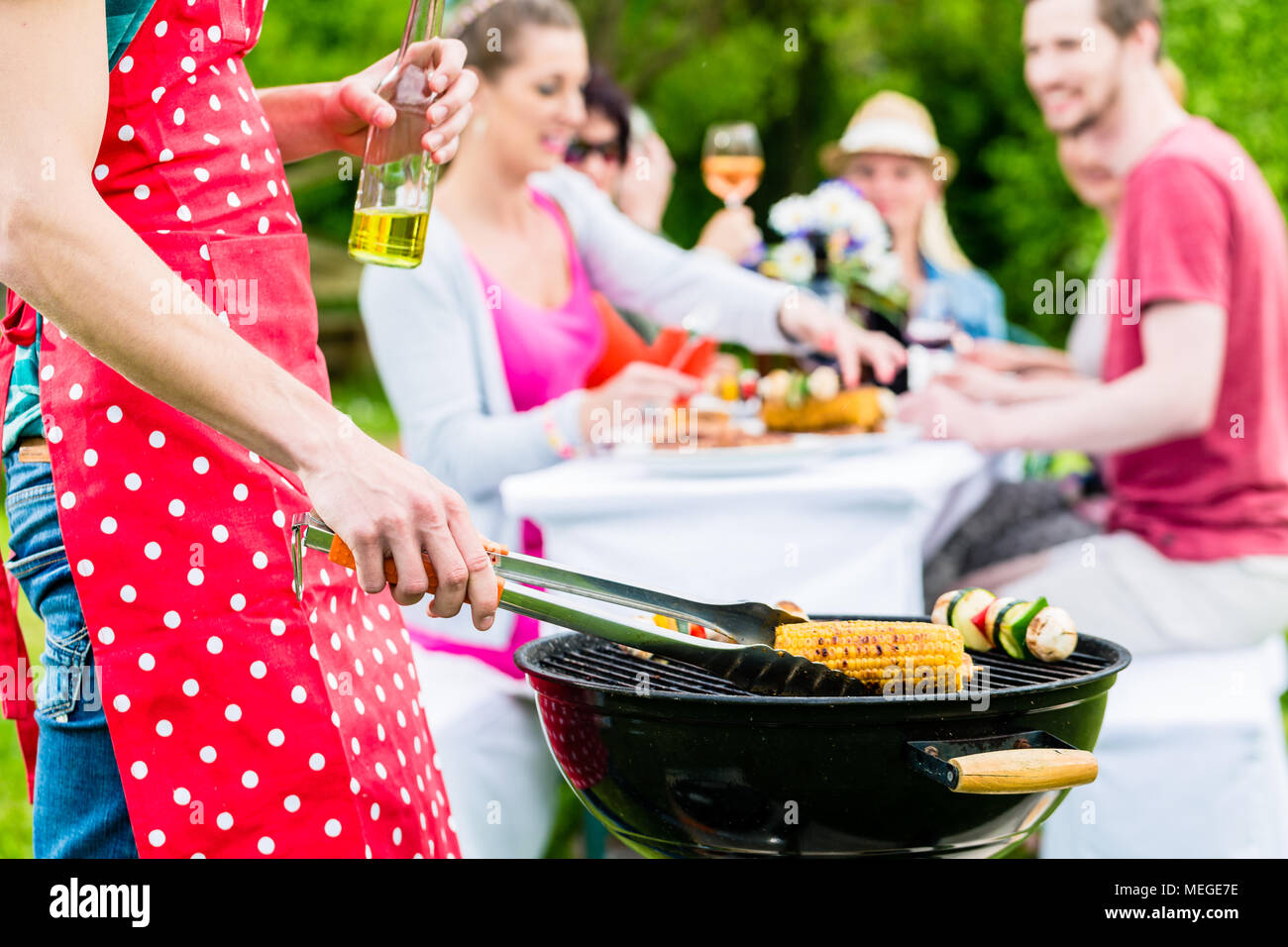 L'uomo cuocere carne e verdure su party in giardino Foto Stock