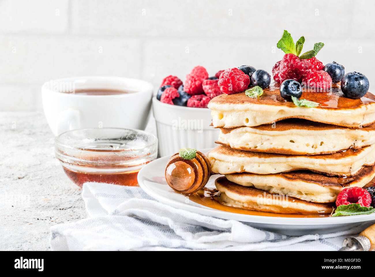 Una sana prima colazione estate,in casa classic american pancake con bacche fresche e miele, mattina pietra grigio chiaro sfondo spazio di copia Foto Stock