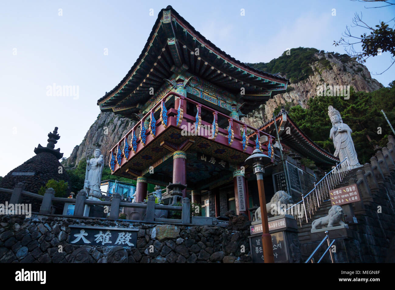 Temple House e statua con tetto colorato in blu ora a tempio Sanbanggulsa, Sanbang-ro, Jeju Island, Corea del Sud Foto Stock