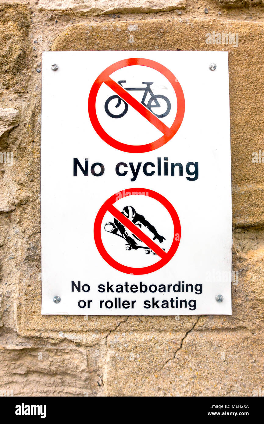 Cartello segnaletico Nessuna Ciclismo No skateboarding o pattinaggio fissato su una parete di pietra Foto Stock